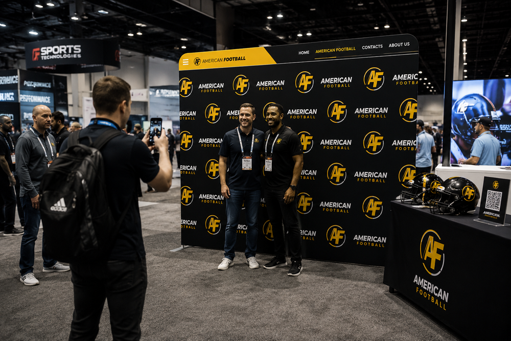 Attendees at a trade show booth using a 10ft straight tension fabric display as a branded step and repeat back wall