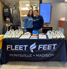 Two people standing behind a custom printed table cover for a business promotion